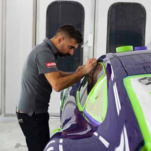 A man working on the hood of a car.